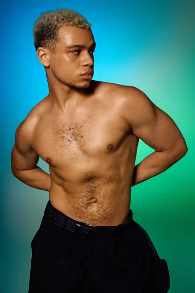 Un jeune homme afro-américain torse nu aux cheveux teints pose artistiquement dans un studio. — Photo de stock