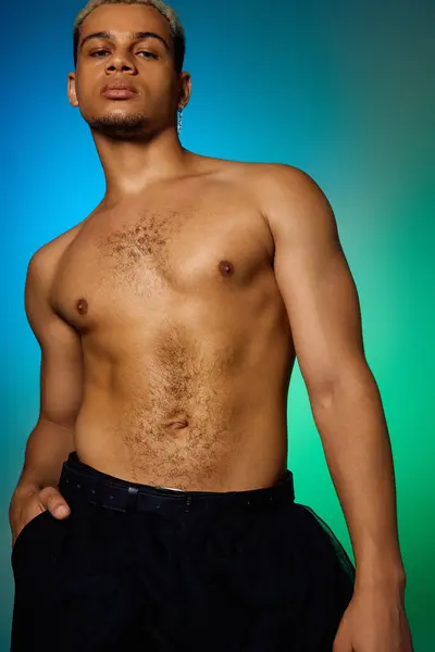 Un joven confiado muestra su forma muscular en un ambiente de estudio con estilo. - foto de stock