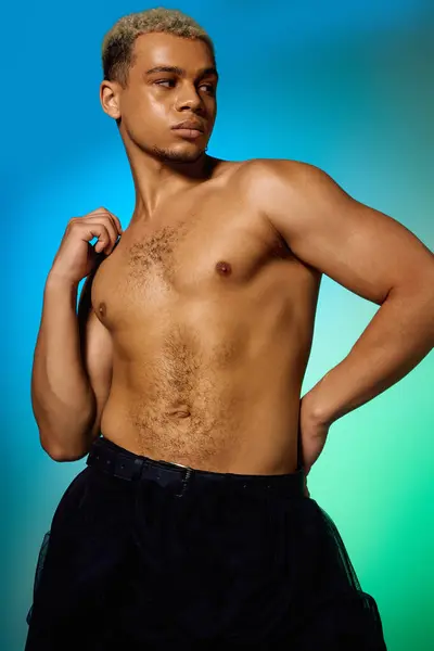 Young african american man poses confidently in a vibrant studio, highlighting fashion and beauty. — Stock Photo