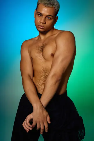 Un joven musculoso posa con confianza, mostrando su pelo teñido y su estilo artístico. - foto de stock