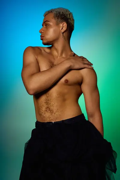 A young shirtless African American man with dyed hair poses artfully in a colorful studio. — Stock Photo