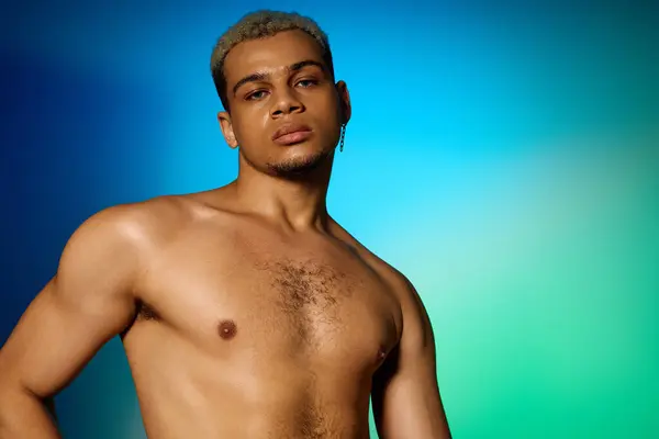 A confident young Black man with dyed hair poses shirtless under studio lights. — Stock Photo