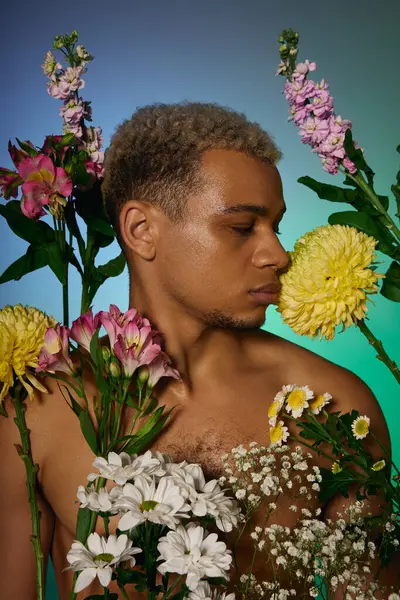 A young African American man poses with a bouquet of fresh flowers in a colorful studio. — Stock Photo