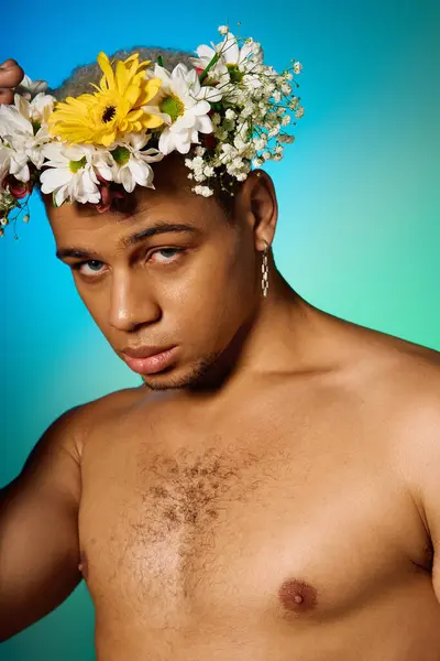 Un joven afroamericano sin camisa posa confiado en un estudio adornado con flores. - foto de stock