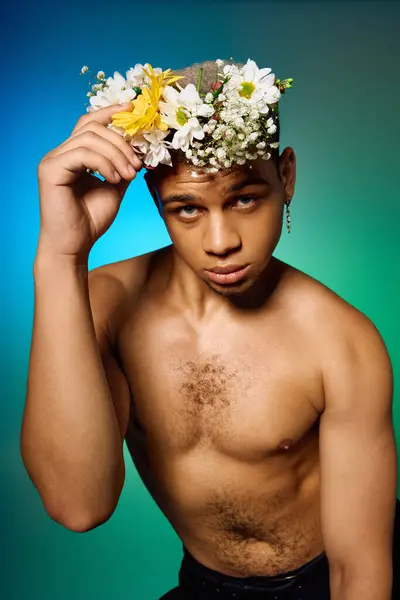 Shirtless young man with dyed hair poses dramatically, adorned with flowers, in a vibrant studio. — Stock Photo