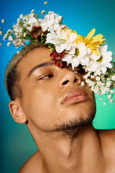 A muscular young man with dyed hair poses shirtless, surrounded by flowers and colors. — Stock Photo