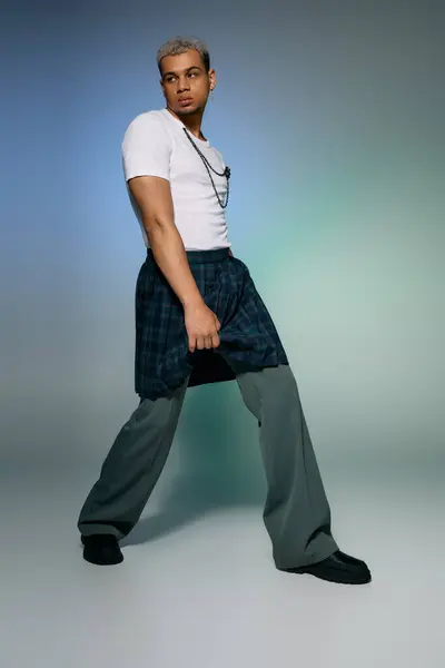A stylish young man confidently poses in a trendy outfit with dyed hair, expressing modern fashion. — Stock Photo