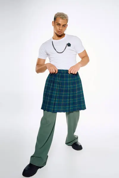 Un joven afroamericano posa con confianza, mezclando elegantes elementos de atuendo en un estudio. - foto de stock
