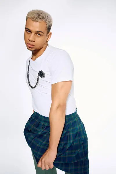 A young Black man with dyed hair showcases a stylish outfit in an artistic studio. — Stock Photo