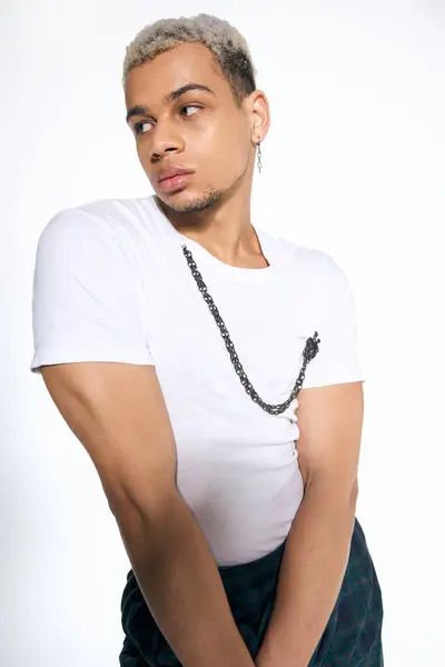 Stylish young african american man with dyed hair poses confidently in a chic studio environment. — Stock Photo