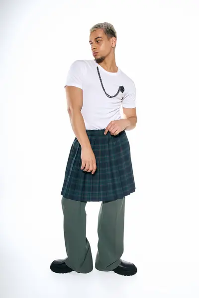 Young man showcases unique fashion choices in a bright studio, blending styles with flair. — Stock Photo