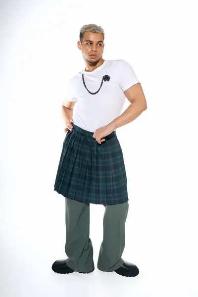 A young african american man in a trendy outfit showcases his unique fashion sense in a studio. — Stock Photo