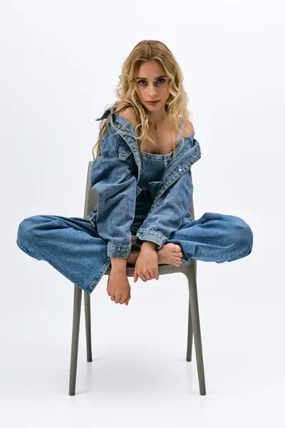 Mulher loira deslumbrante mostra seu senso de moda com uma pose cadeira única em um ambiente elegante. — Fotografia de Stock