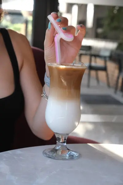 Iced coffee with milk. Iced coffee latte . Woman holding glass cup of iced coffee.