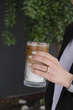 Sütlü buzlu kahve. Buzlu kahve. Elinde bir bardak buzlu kahve tutan kadın..