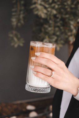 Sütlü buzlu kahve. Buzlu kahve. Elinde bir bardak buzlu kahve tutan kadın..