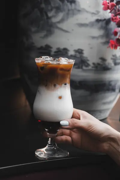 Iced coffee with milk. Iced coffee latte . Woman holding glass cup of iced coffee.