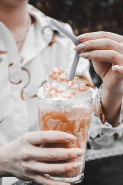 Sütlü buzlu kahve. Buzlu kahve. Elinde bir bardak buzlu kahve tutan kadın..