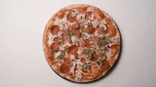 Homemade Italian pizza with mozzarella cheese, salami, tomato sauce, pepper, arugula and spices