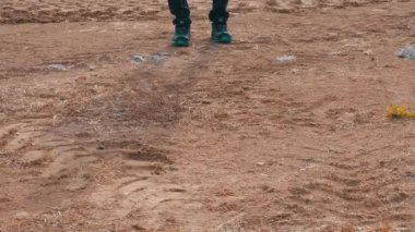 Bir adam toprak araziye basıyor ve yürüyor.