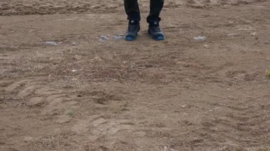 Bir adam toprak araziye basıyor ve yürüyor.