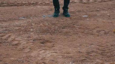 Bir adam toprak araziye basıyor ve yürüyor.