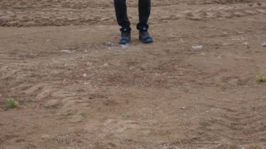 Bir adam toprak araziye basıyor ve yürüyor.