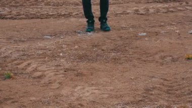 Bir adam toprak araziye basıyor ve yürüyor.
