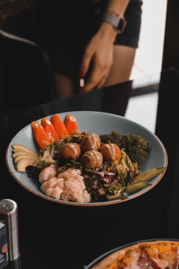 Sebzeli, zeytinli, otlu ve yoğurt soslu falafel salatası kasesi..