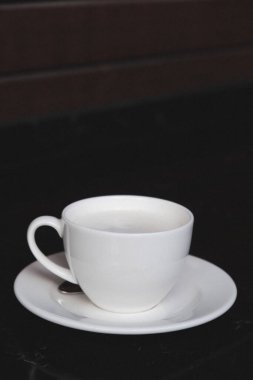 Minimalist bir masada cam bardağa doldurulmuş kahve.