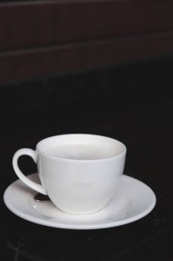 Minimalist bir masada cam bardağa doldurulmuş kahve.