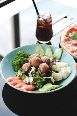 Sebzeli, zeytinli, otlu ve yoğurt soslu falafel salatası kasesi..