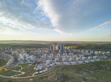 Modiin, Israel, January 12, 2023 Construction of a multi-story residential building and a large new residential area overlooking a green park with trees and a lawn next to residential buildings