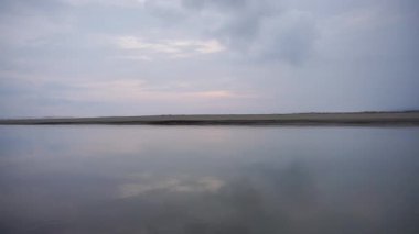 Öğleden sonra güzel bir sahil manzarası var. Küçük dalgaları ve kumsalı görebilirsiniz.