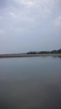 Dikey güzel plaj portresi görüntüsü öğleden sonra, küçük dalgaları ve kumsalı görebilirsiniz.