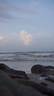 Dikey güzel plaj portresi görüntüsü öğleden sonra, küçük dalgaları ve kumsalı görebilirsiniz.