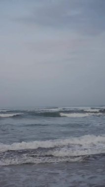 Dikey güzel plaj portresi görüntüsü öğleden sonra, küçük dalgaları ve kumsalı görebilirsiniz.