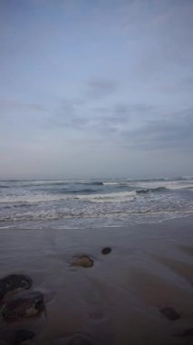 Dikey güzel plaj portresi görüntüsü öğleden sonra, küçük dalgaları ve kumsalı görebilirsiniz.