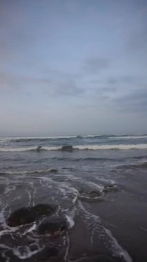 Dikey güzel plaj portresi görüntüsü öğleden sonra, küçük dalgaları ve kumsalı görebilirsiniz.