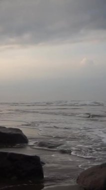 Dikey güzel plaj portresi görüntüsü öğleden sonra, küçük dalgaları ve kumsalı görebilirsiniz.