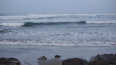 Öğleden sonra güzel bir sahil manzarası görünür küçük dalgalar ve kumsal.