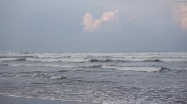 Öğleden sonra güzel bir sahil manzarası görünür küçük dalgalar ve kumsal.