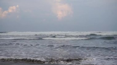 Öğleden sonra güzel bir sahil manzarası görünür küçük dalgalar ve kumsal.