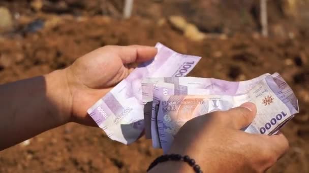 一个人的手在一个种植园的一个空地上数着十卢比钞票 — 图库视频影像
