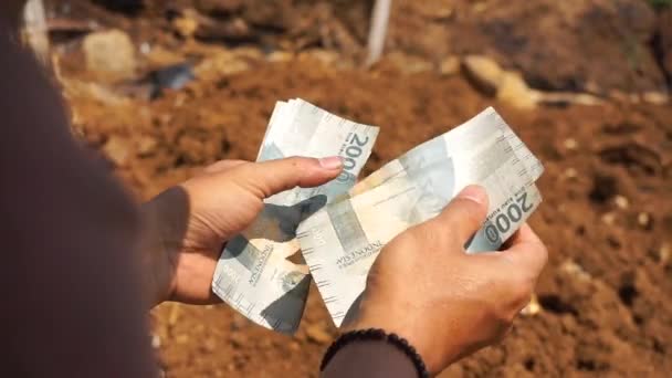 一个人的手在种植园的一个空地上数着两千卢比钞票 — 图库视频影像