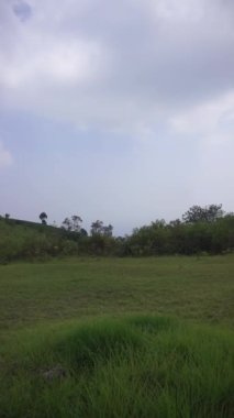 Doğal manzara dağları, doğal panorama tepeleri, ve uzun yeşil ağaçlardan oluşan ormanlar ve bulutlu mavi gökyüzünün altında yeşil tarlalar.