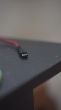Siyah bir masanın üzerinde kırmızı kabloyla C tipi fiş.