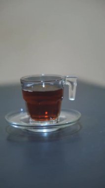 Siyah bir masanın üzerine beyaz cam bir fincana çay döküyorum.