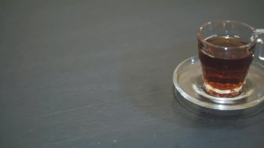 Siyah bir masanın üzerine beyaz cam bir fincana çay döküyorum.