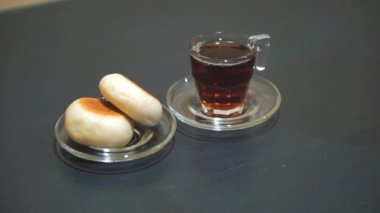 Bir fincan çay ve yeşil fasulye ekmeği, siyah masada yemeye hazır.